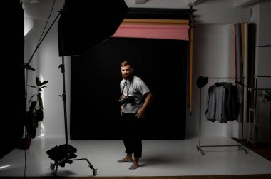 Profesyonel yakışıklı sakallı erkek fotoğrafçı. Fotoğraf stüdyosunda bir sürü klasik fotoğraf makinesi var.