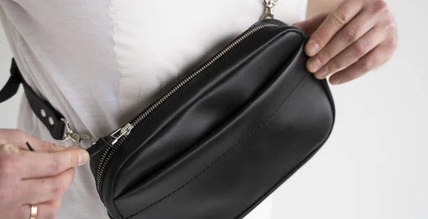 Details of leather black handmade bag over his shoulder. Dark designer banana bag. Comfortable small bag for walking