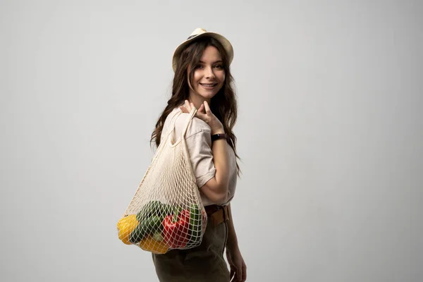 stock image Young woman holding mesh grocery bag with vegetables Concept of no plastic. Zero waste, plastic free. Eco friendly concept. Sustainable lifestyle