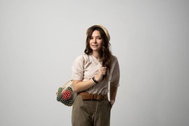 Sıfır atık. Tekrar kullanılabilir pamuk alışveriş poşeti taşıyan genç bir kadın marketten aldıklarıyla birlikte. Plastiksiz kavram. Sıfır atık, plastik yok. Çevre dostu kavram. Sürdürülebilir yaşam tarzı