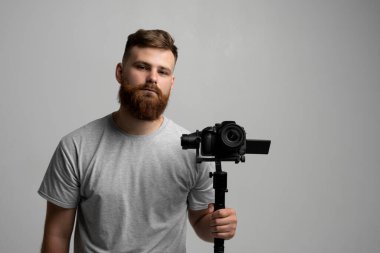 Videographer making a good footage using steadicam. Cameraman creator with a stabilizer in his hands takes a video on the slr video camera on white background. Creating a video content