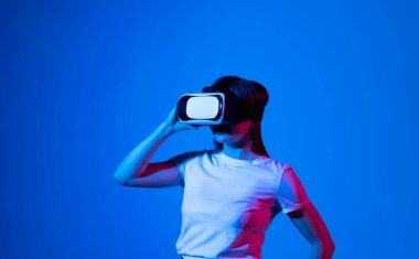 VR gözlüklü esmer kadın. Sanal gerçeklikteki kendine güvenen genç kadın stüdyoda çalışırken havayı işaret ediyor.