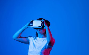 VR, Technology, Video Game and Metaverse Concept. Brunette woman exploring or playing in virtual augmented reality with vr goggles headset in the Metaverse