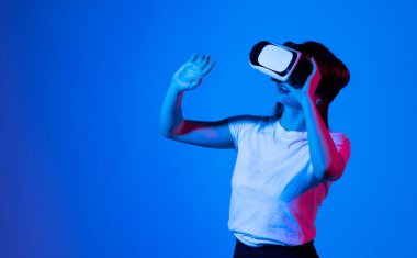 Woman in VR headset using finger to touch on imaginary panel viewing on VR device. VR is a computer technology that simulates a physical presence and allows to interact with environment