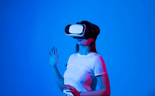 Brunette woman in VR glasses. Confident young woman in virtual reality headset pointing in the air while working in studio