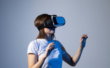 Genç bir kadın simülasyon oyunu oynamak için kulaklık kullanıyor. Sanal gerçeklik 3D video izliyor. VR gözlüklü kız etrafa bakıyor.