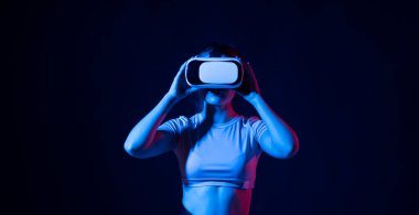 Kadın sanal gerçeklikten zevk alıyor. VR kulaklıklı kadın görünmez ekrana dokunuyor. Gelecekteki teknoloji konsepti