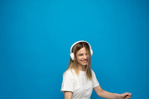 Šťastná Blondýnka Bílými Sluchátky Poslouchající Hudbu Tančící Modrém Pozadí Žena — Stock fotografie