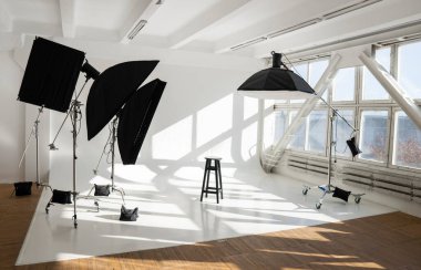 Profesyonel ışıklandırma ekipmanları, bağlar, stantlar, yumuşak kutular modern fotoğraf stüdyosunda büyük bir günışığı penceresi olan büyük bir siklonama.