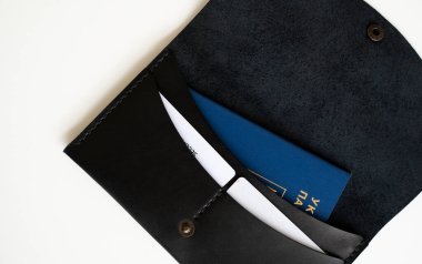 İçinde Ukrayna pasaportu ve kartları olan açık siyah deri bir cüzdanın en üst görüntüsü. Resim el yapımı cüzdanın dokusunu, dikişini ve pratik tasarımını vurgular..