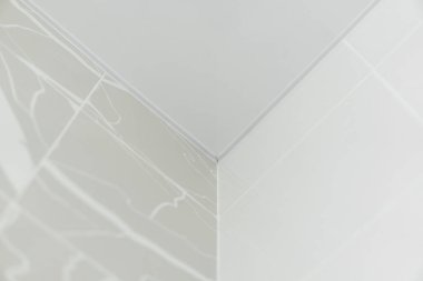 Seramik duvar fayansları ve ince mermer çizgileri olan temiz beyaz bir köşenin geometrik soyut görüntüsü modern bir minimalist mimari kompozisyon oluşturur..