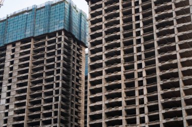 Modern yapının yapısal unsurları arasında derinlik, tekrarlama ve gölge oyunlarına odaklanan, tamamlanmamış iki beton kulenin yoğun çerçeveli çekimi.
