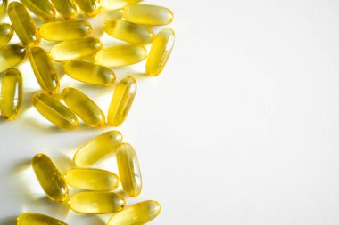 Yayımsal veya ticari kullanımda sağlık, diyet ve refah temaları için ideal geniş beyaz alan ile düzenlenmiş parlak sarı omega-3 kapsüllerini gösteren yüksek anahtarlı bir çekim.
