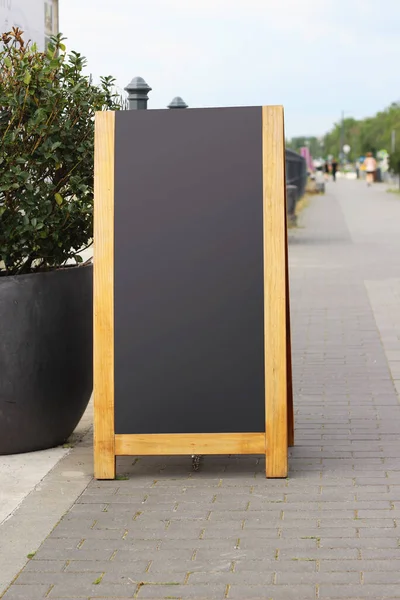 Empty black sandwich chalkboard menu board stand on a street.