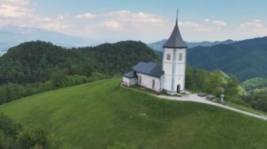 Slovenya 'nın Jamnik kentindeki tepedeki St. Primus ve St. Felician Katolik Kilisesi. Yürüyüş, turizm konseptleri. İHA atışı, 4K, 60FPS
