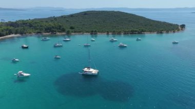Hırvatistan 'ın Adriyatik Denizi' ndeki Ugljan adasındaki güzel bir Muline körfezine demirlemiş tekneler, yelkenliler ve yatlar. Lüks, seyahat, turizm, tatil ve bedava yaşam tarzı kavramları. Hava aracı atışı. 4K 60FPS