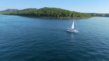 Hırvatistan 'ın Adriyatik Denizi' ndeki Zadar yakınlarındaki Ugljan adasından geçen yelkenli. Seyahat, turizm, tatil, bedava yaşam tarzı ve lüks kavramlar. Hava kaydırağı ve pan drone görüntüsü. 4K 60FPS