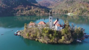 Slovenya 'daki Bled Gölü' ndeki Katolik kilisesinin yörüngesinde. Sonbaharda turistik bir eğlence ve dönüm noktası. Seyahat, turizm ve inanç kavramları. 4K, 60FPS