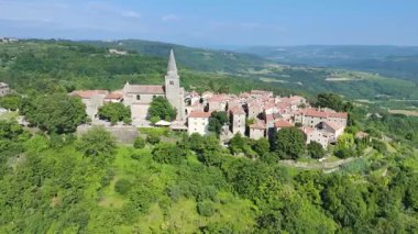 Hırvatistan 'ın Istria kentindeki eski Groznjan - Grisignana kentinin hava manzarası. Sanatçılar Kasabası olarak bilinen tarihi bir yer. Kilise kulesi ve tepedeki eski binalar. Turizm, eğlence ve seyahat kavramları. 4K