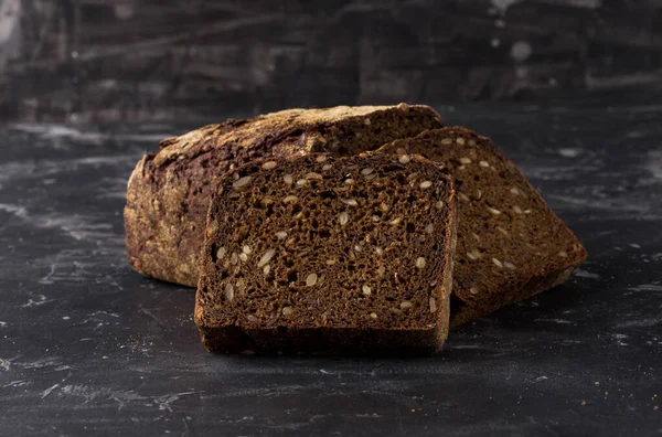 stock image Rye black bread with seeds  on dark board background