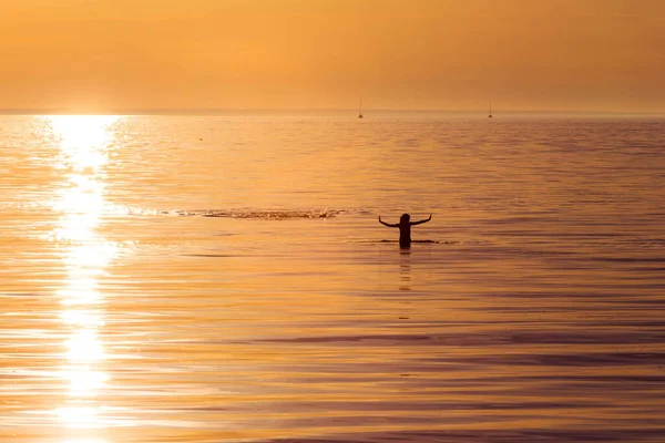 夕日の光の中で海の女性のシルエット — ストック写真
