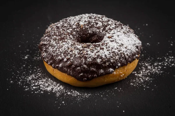 Sprinkling sugar powder on delicious donut topped with chocolate