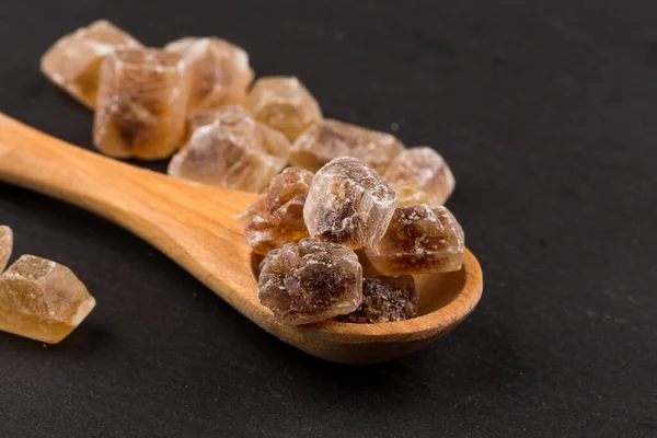 Stock image caramelized candy brown sugar in wooden spoon on a dark stone board