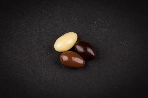 stock image almonds in white, dark, milk chocolate in a bowl on stone board