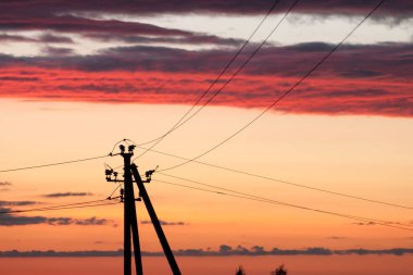 Gün batımında renkli gökyüzüne karşı elektrik hattı