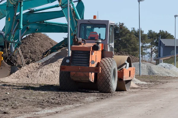 挖掘机和沥青压实机卡车在建筑工地上 — 图库照片