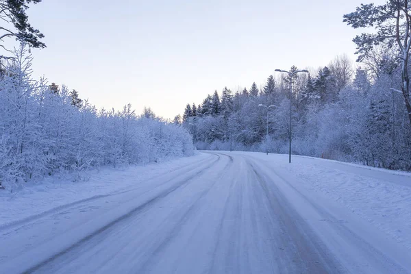 日没時に雪で覆われている道路で冬の森 — ストック写真