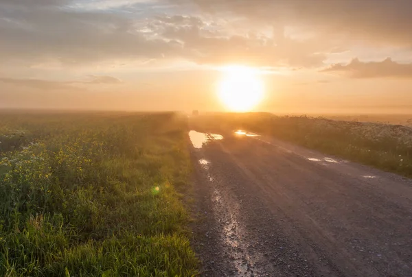霧と日没農村道路上の車 — ストック写真