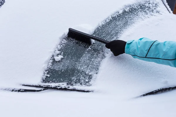 冬の車から雪を掃除する女 ストック写真