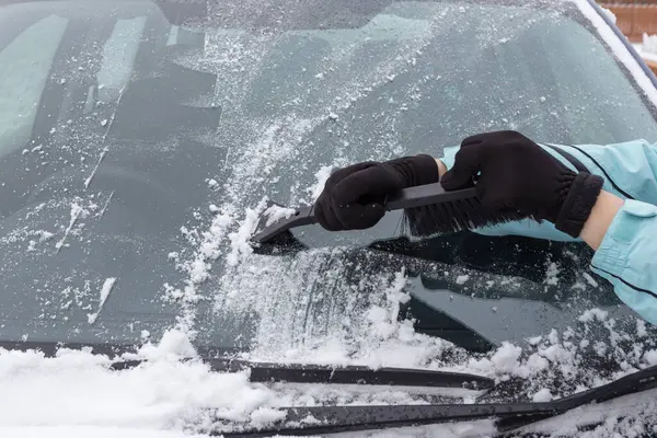 冬の車から雪を掃除する女 ストックフォト