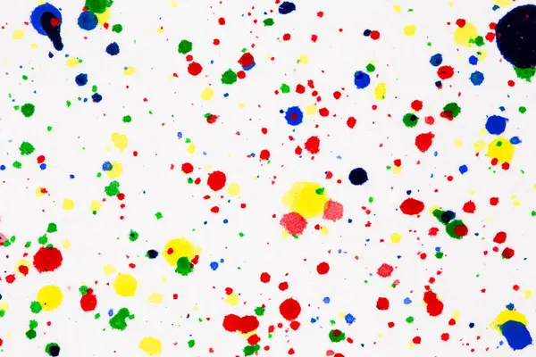 Colorful ink splashes. Paint splatters on bright material. Multi color dots. Watercolor on white paper.