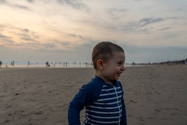Genç bir erkek çocuk Seminyak, Bali 'de sahilde oynuyor.