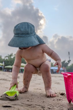 Genç bir erkek çocuk Seminyak, Bali 'de sahilde oynuyor.