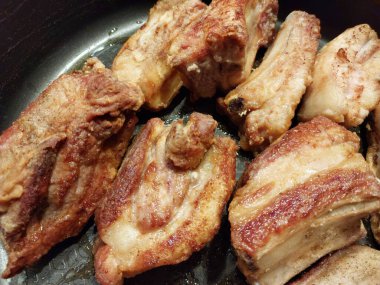 Siyah tabakta kızarmış tavuk bacağı.