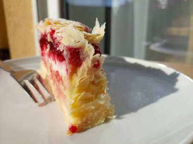 Tahta tabakta krema olan bir parça peynirli pasta.