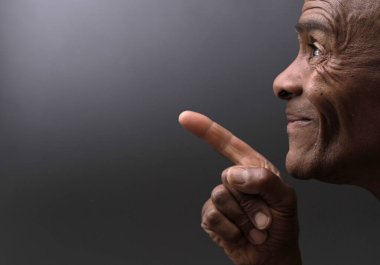 Adam koyu arkaplanlı parmağını gösterip insanların resimlerini basıyor.