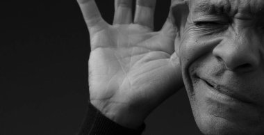 Gri arka planda sağırlık ve işitme kaybı yaşayan bir adam.