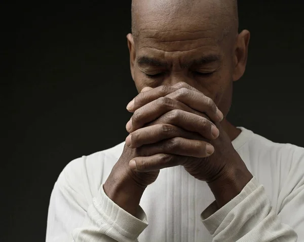 Siyah adam, insanların resimleriyle birlikte gri siyah arka planda Tanrı 'ya dua ediyor.