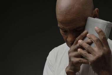 Siyah adam, insanların resimleriyle birlikte gri siyah arka planda Tanrı 'ya dua ediyor.