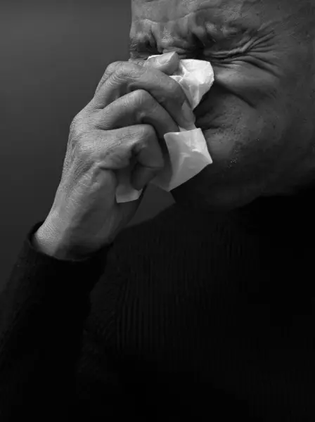 blowing nose after catching the cold and flu with grey background with people stock image stock photo