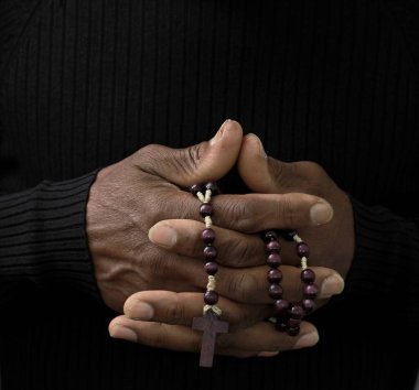 Adam Tanrı 'ya ellerinin birliğiyle dua ediyor Karayipli adam gri siyah arka planda dua ediyor insanların resimli çorap fotoğraflarıyla.