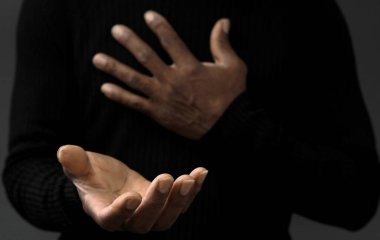 Adam Tanrı 'ya ellerinin birliğiyle dua ediyor Karayipli adam gri siyah arka planda dua ediyor insanların resimli çorap fotoğraflarıyla.