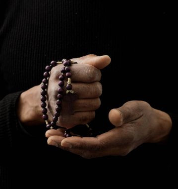 Adam Tanrı 'ya ellerinin birliğiyle dua ediyor Karayipli adam gri siyah arka planda dua ediyor insanların resimli çorap fotoğraflarıyla.