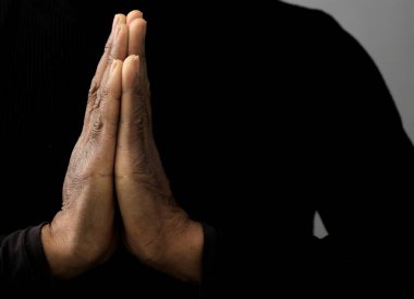 Adam Tanrı 'ya ellerinin birliğiyle dua ediyor Karayipli adam gri siyah arka planda dua ediyor insanların resimli çorap fotoğraflarıyla.