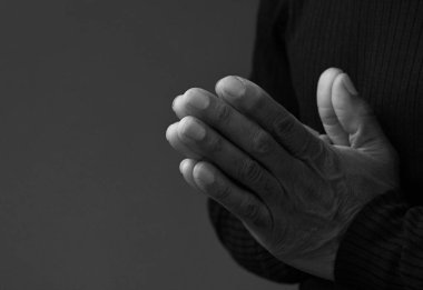 Adam Tanrı 'ya ellerinin birliğiyle dua ediyor Karayipli adam gri siyah arka planda dua ediyor insanların resimli çorap fotoğraflarıyla.