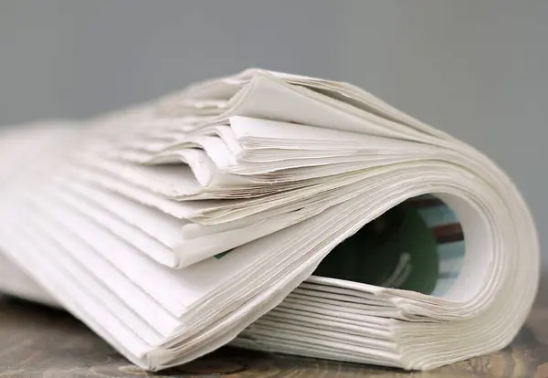 newspaper rolled up and sitting on a table no people stock image stock photo